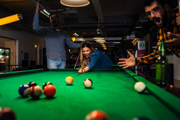Group of friends having fun in bar playing billiard together.