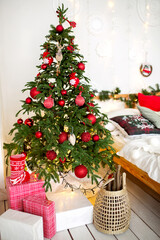 Decorated Christmas tree in the living room with sofa, blanket, lights garlands. Bedroom with a...