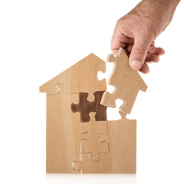 Hand bulding houseout of puzzle pieces on white background