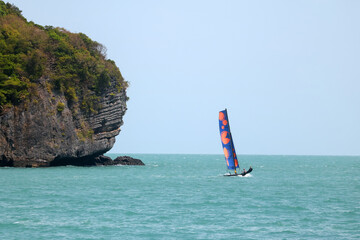 A sailboat is sailing around the islands in the sea