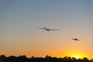 Fototapeta na wymiar Remorquage d'un planeur avec un avion au levé du soleil