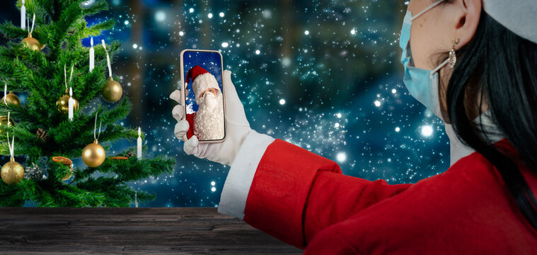 An Elf With A Face Mask Communicates Via Mobile Phone With Santa