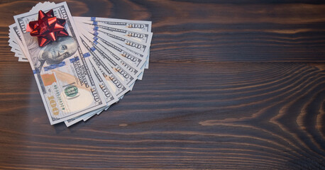 Stack Of Hundred-Dollar Banknotes gift for the new year or christmas. with red bow flat lay on a wooden background. top view