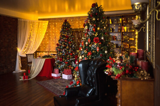 Christmas interior of the dark living room of the house. Christmas tree, lights of garlands on the walls, library Cabinet, books on the shelves. Luxury interior. New Year, red and gold balls.