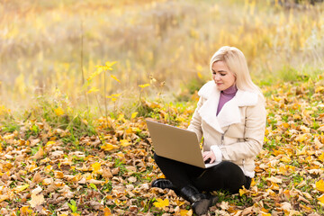 woman relaxes in park while working on her laptop