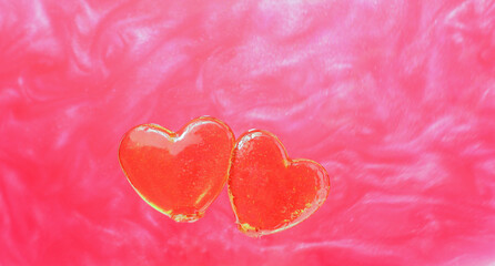 Obraz na płótnie Canvas Valentine for the holiday. Two candy bars in the shape of red hearts on a shimmering pink background. Celebration background. Romance