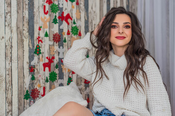 Fototapeta premium happy young woman sitting near christmas tree. Happy young lady with curlu hair gifts by the fireplace near the Christmas tree. New year concept. Xmas.
