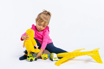 A little concentrated girl plays and puts a doll on a truck. The concept of gender stereotypes....