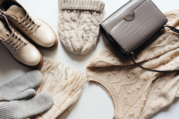 winter fashion set of woman clothes in neutral tones: warm sweater, hat, mittens, shoes and handbag...
