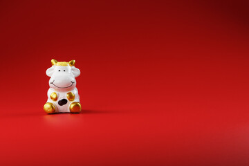 Christmas toy of a cow made of ceramic on a red background. 2021 year of the Bull, cow. New year's symbol