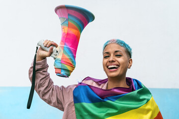 Young woman celebrating gay pride event wearing rainbow flag symbol of Lgbt social movement