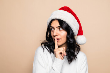 Young woman doing silence gesture with christmas hat over isolated background