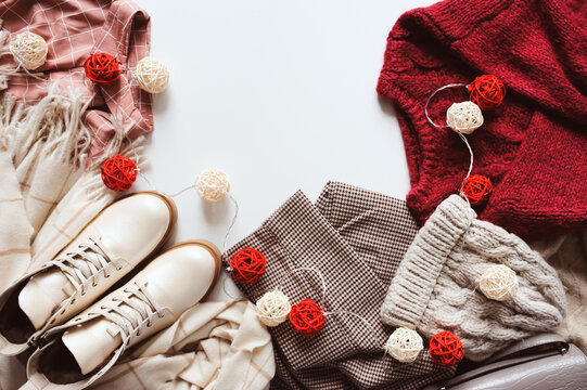 Online Christmas shopping and sale concept. Flat lay of woman fashion clothes in red and beige tones. Shoes, sweater, warm hat and scarf.