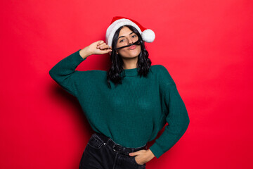 Young woman wearing santa hat have fun isolated on red background