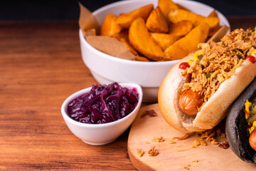 American traditional fast food Hotdog with fresh organic bread bun white wheat and black charcoal sausage ketchup mustard for meal with roasted onion pickle and French fries wedges and coleslaw