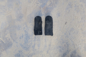 two little black gloves laying on a sandy metal plate