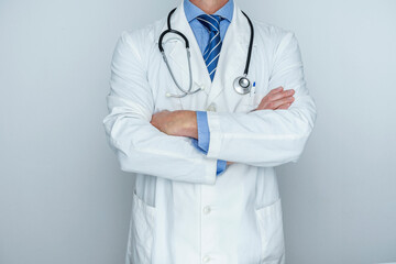 ELEGANT DOCTOR WITH STETHOSCOPE, WHITE COAT AND FOLDED ARMS. TRUSTED DOCTOR AND HEALTH INSURANCE CONCEPT.