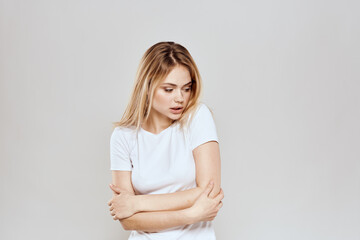 Obraz premium cheerful blonde in a white t-shirt gesturing with her hands light background