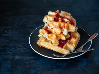 Cottage cheese waffles with raspberry jam on a cramped plate with dessert forks