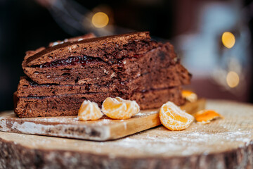 piece of chocolate cake on a wooden bord sprinkled with sugar powder in the dark background