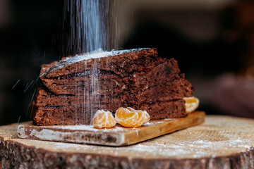 chocolate cake on a wooden bord sprinkled with sugar powder
