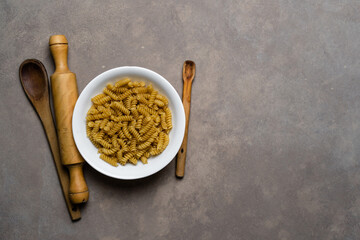 Top view of raw fusilli pasta on white plate.