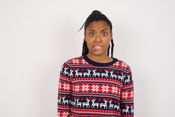 Young beautiful African American woman wearing Christmas sweater against white wall,  being nervous...