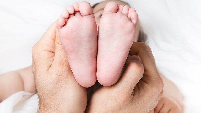 dad is holding the baby's tiny feet. Small baby feet on male hands close up. Happy family concept. Beautiful conceptual image of fatherhood. top view. copy space