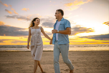 Happy couple running along the beach on sunset. . Image with selective focus.