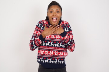 Happy smiling Young beautiful African American woman wearing Christmas sweater against white wall...