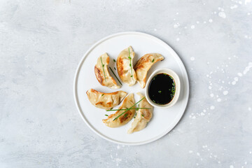 Delicious Japanese gyoza dumplings fried on a white plate with soy sauce