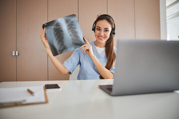 Cheerful female doctor using laptop for online consultation