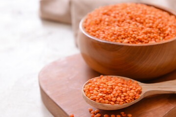Bowl and spoon with raw lentils on table, closeup