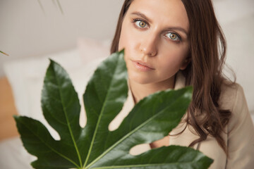 Happy young brunette woman holding delicate white flowers on beige background. Concept body and face skin care, smoothness and tenderness