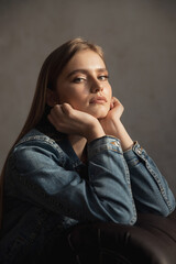 Portrait of young blonde woman in denim jacket on sofa