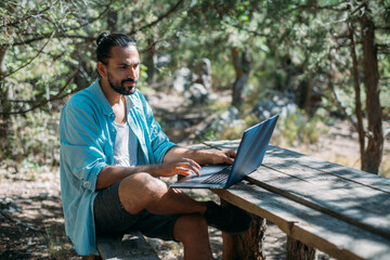 Obraz premium Male tourist working on a laptop outdoors in a camping.