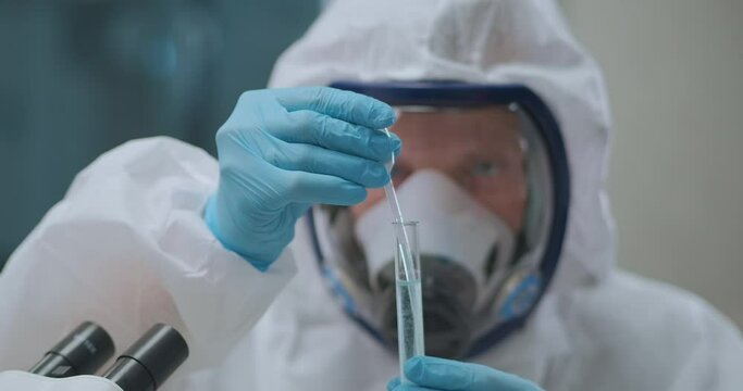 microbiologist is taking liquid with dangerous bacteria from test tube by pipette in laboratory, working with chemicals and toxins, closeup
