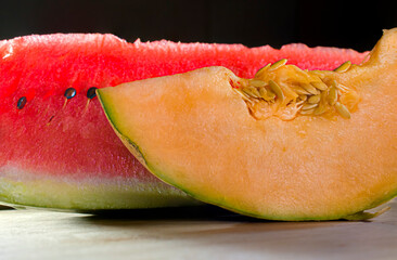 melon and watermelon still life on a wooden cutting board with rim light and a black background