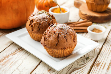 Plate with tasty pumpkin muffins on table