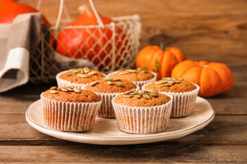 Plate with tasty pumpkin muffins on table