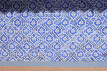 The rhythm of light and color on the wall of the church decorated with blue Thai ceramic tiles