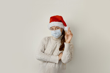 Young woman wearing protection mask for coronavirus disease over beige background smiling cheerful pointing with hand and finger up to the side