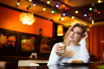 Beautiful woman drinking coffee at the cafe wintertime.