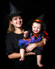 family mother and baby daughter over dark background ready for the Halloween