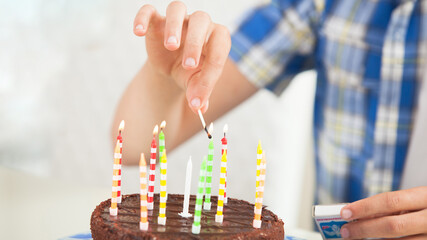 Teenager lights the candles on a birthday cake
