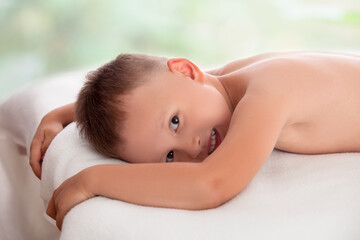 Obraz na płótnie Canvas Happy boy lying on a massage table waiting for massage