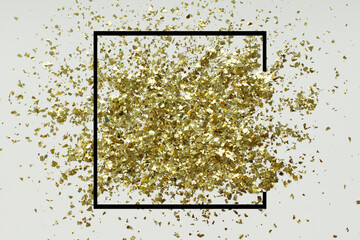 Golden glitter sand texture on white, abstract background. Gold shimmer decoration, shiny and black frame, top view, copy space. Holidays and glamour concept.