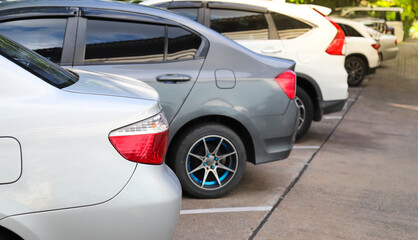 Closeup of rear side of bronze car and other cars parking in parking area.