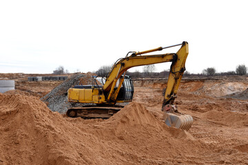 Fototapeta na wymiar Excavator digs dirt during roadwork at construction site. Heavy machinery and earth-moving equipment