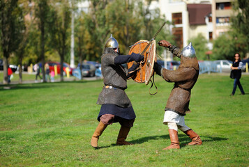 Reenactors dressed in armor of Old Russian footmen reconstructing swords fight
